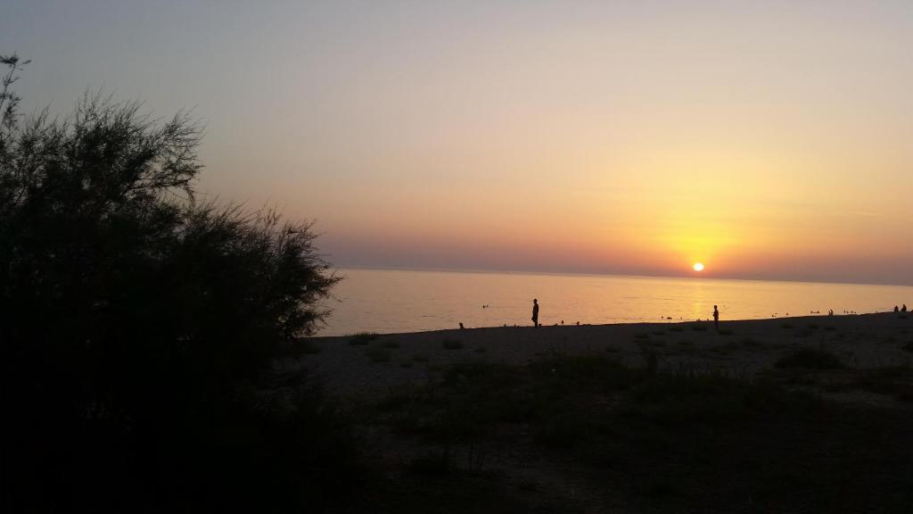 una persona parada en una playa al atardecer en Kanali Beach House, en Kanali