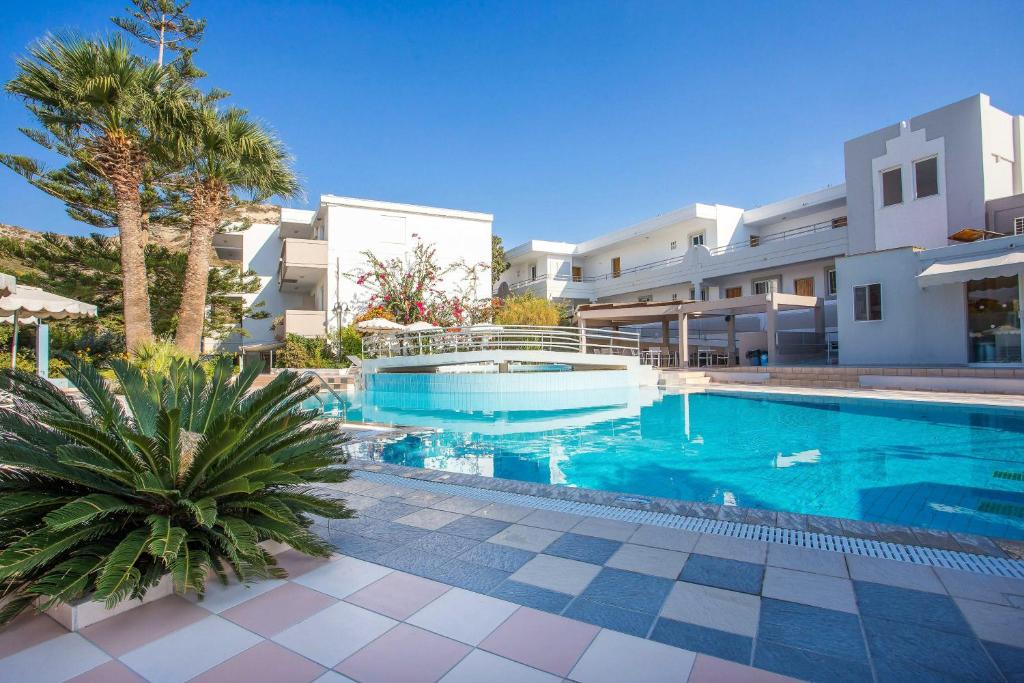 una piscina di fronte a un edificio con palme di Irinna Hotel-Apartments a Faliraki