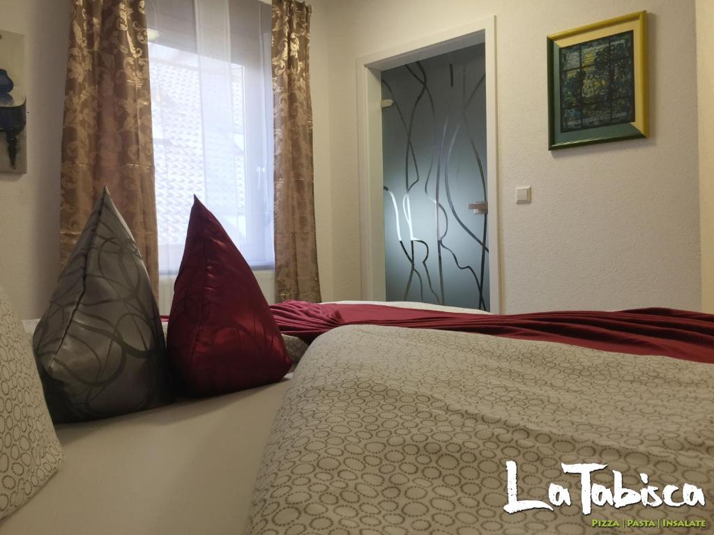 um quarto com uma cama com almofadas vermelhas em Hotel Schurwald em Rechberghausen