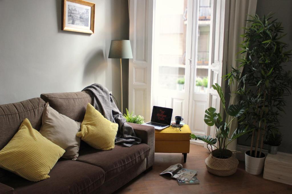 sala de estar con sofá y mesa con ordenador portátil en The Art Boutique Colon, en Valencia