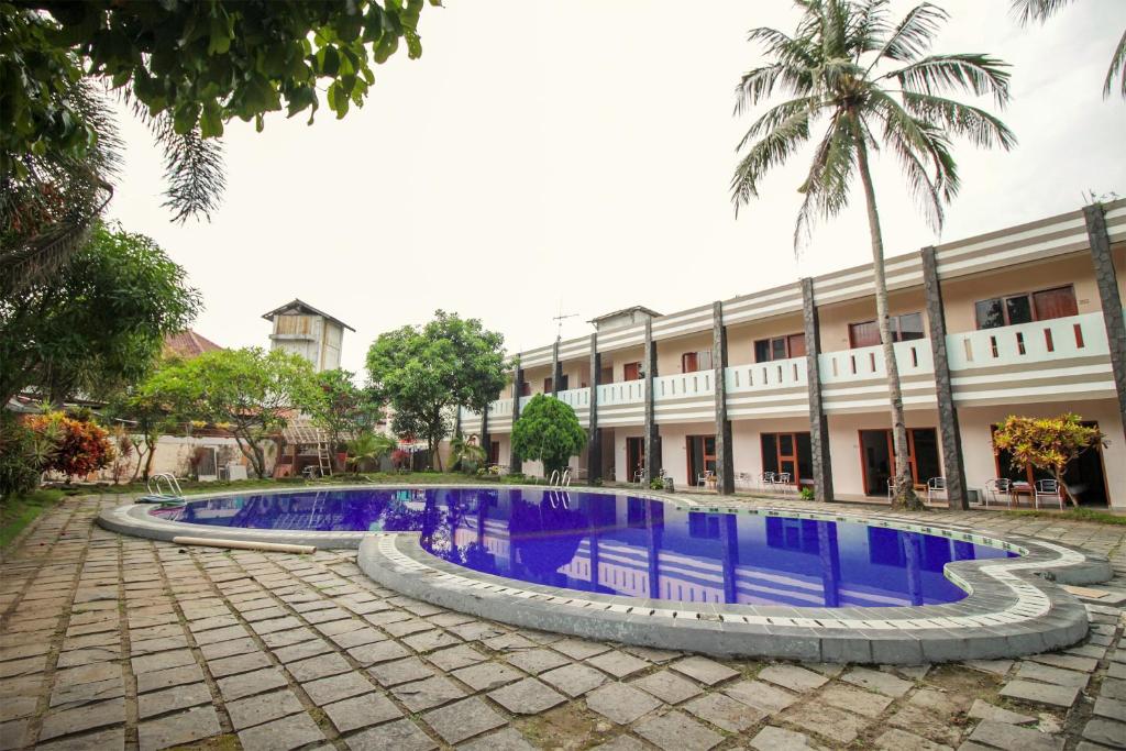 a hotel with a swimming pool in front of a building at RedDoorz Plus At Hotel Sofia Pangandaran in Pangandaran