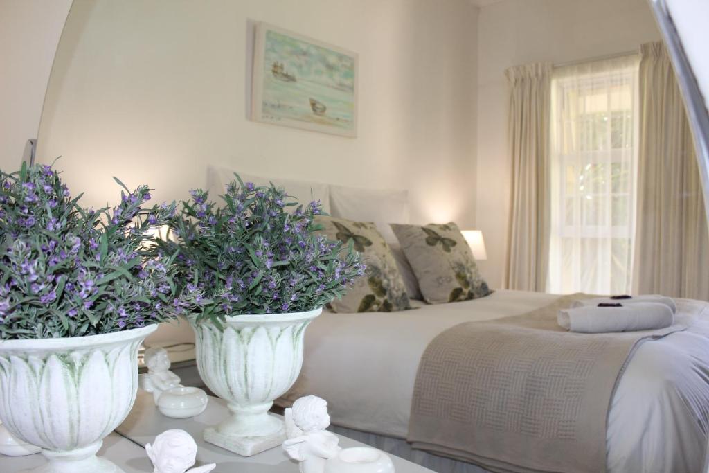 a bedroom with two white vases with flowers on a bed at van Biljon Cottage No Loadshedding in Oudtshoorn