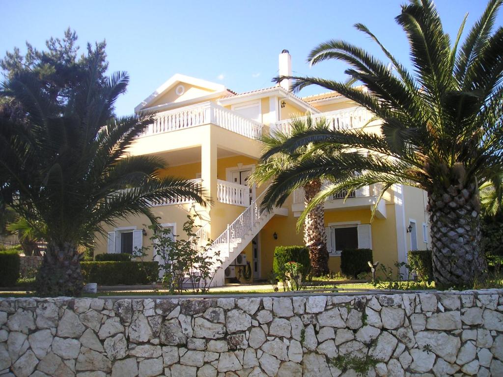 a large white house with palm trees in front of it at Nikolaos Studios Skala in Skala Kefalonias
