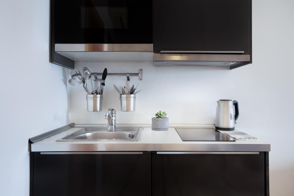 a kitchen with black cabinets and a sink at Plaza Regency Hotels in Sliema