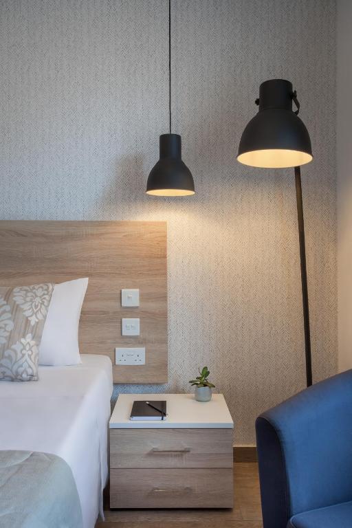 a bedroom with two lamps and a bed and a chair at Plaza Regency Hotels in Sliema