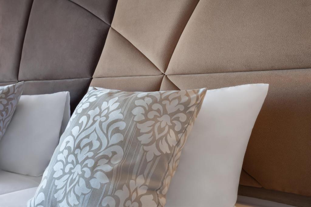 a bed with a brown headboard with a pillow at Plaza Regency Hotels in Sliema