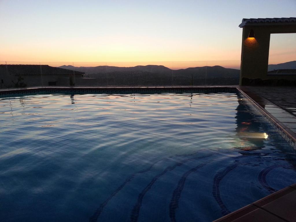 uma piscina com o pôr-do-sol ao fundo em Amarilla em Cumbre del Sol