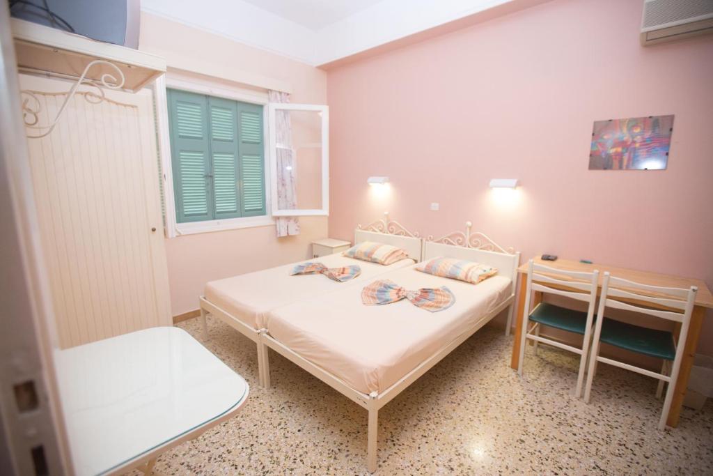 a small bedroom with two beds and a table at Marina rooms in Argostoli