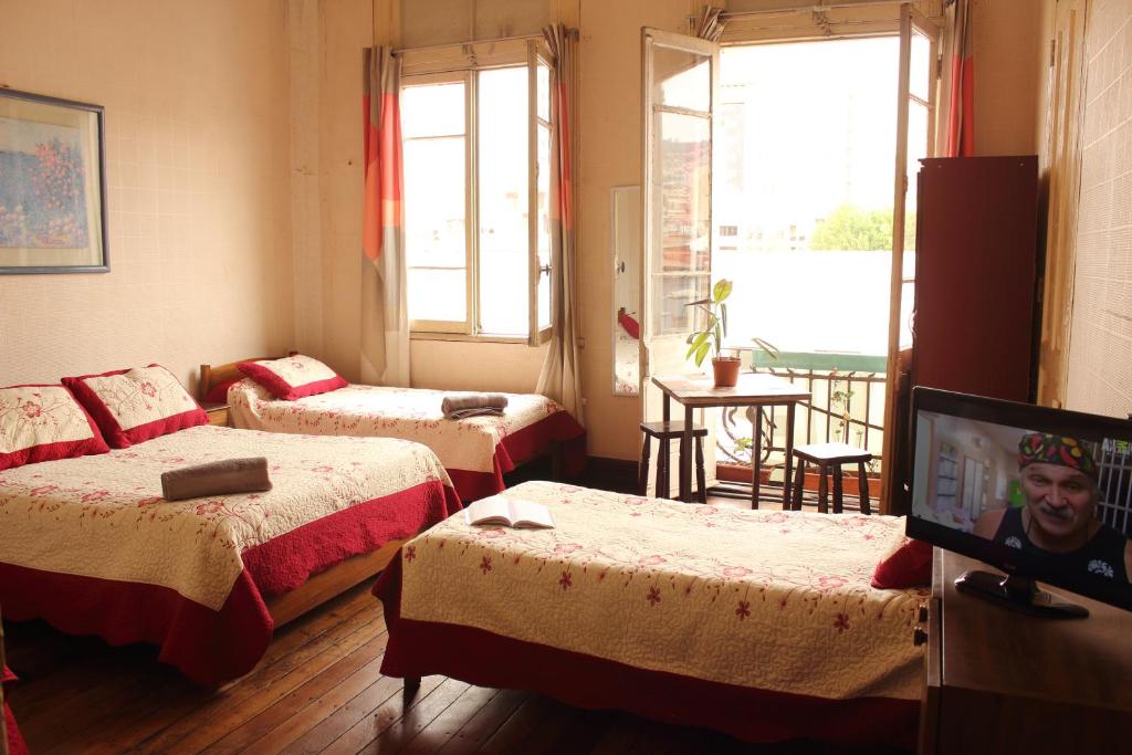 a room with three beds and a flat screen tv at Hostal Fiorenttina in Valparaíso