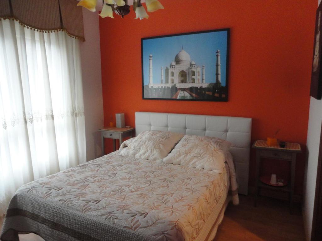 1 dormitorio con 1 cama con pared de color naranja en Pensión Vegadeo Gijón, en Gijón