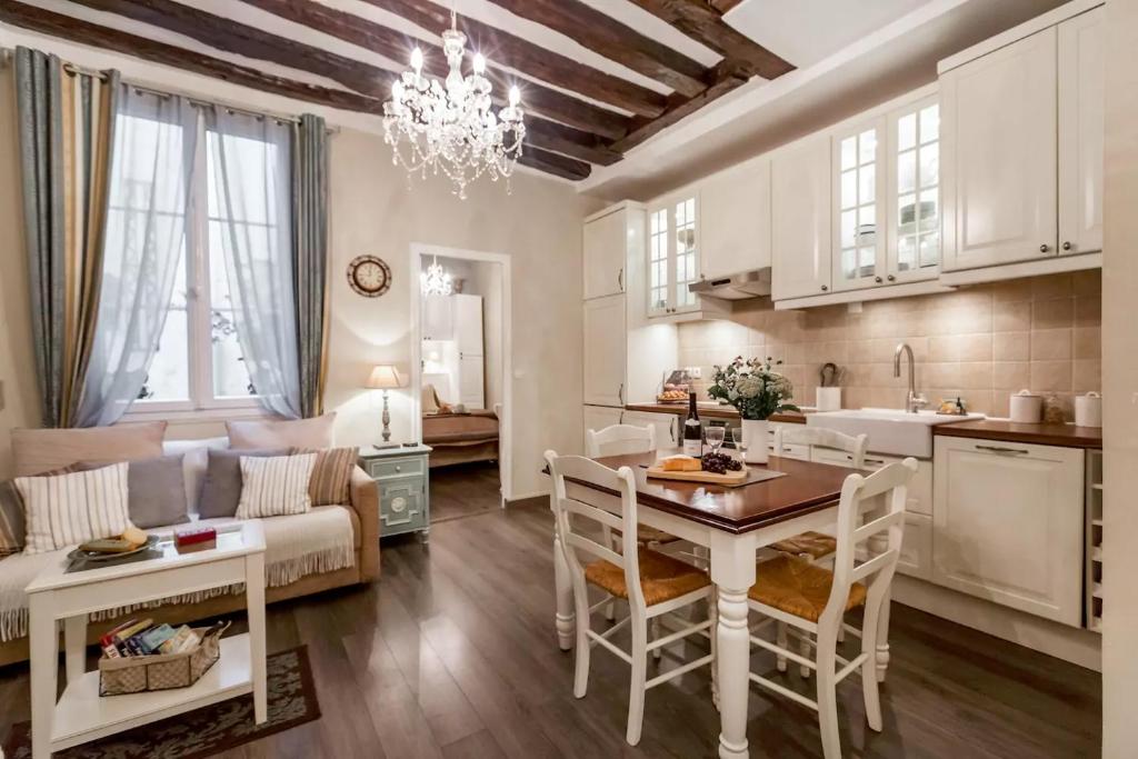 een keuken en een woonkamer met een tafel en stoelen bij Le Jardin Du Marais in Parijs