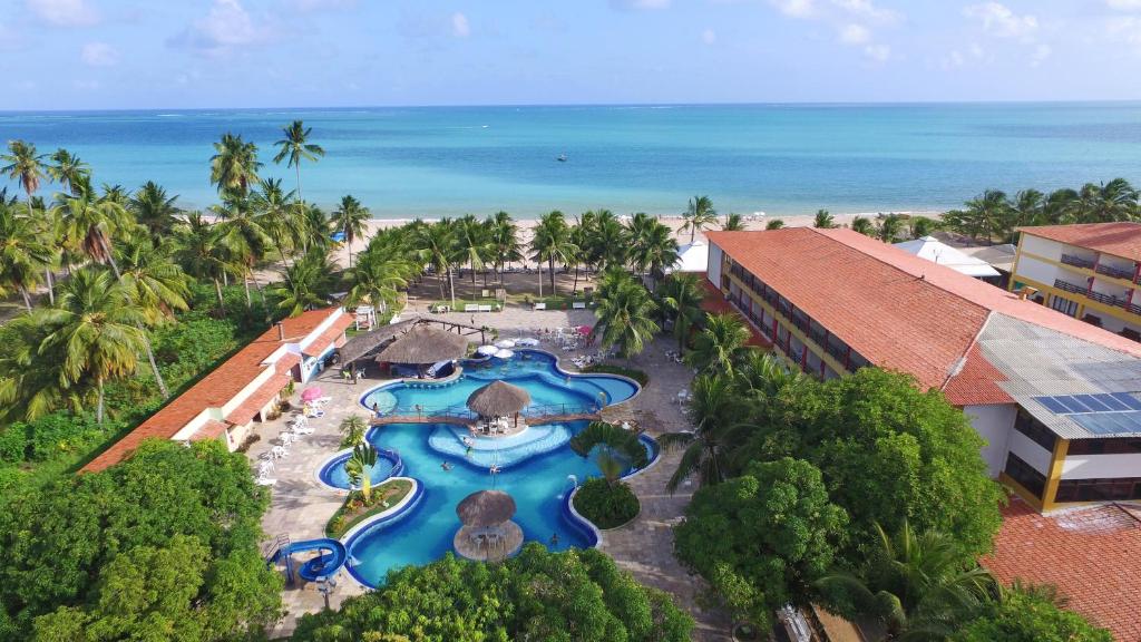 an aerial view of a resort with a pool and the ocean at Hotel Praia Dourada in Maragogi