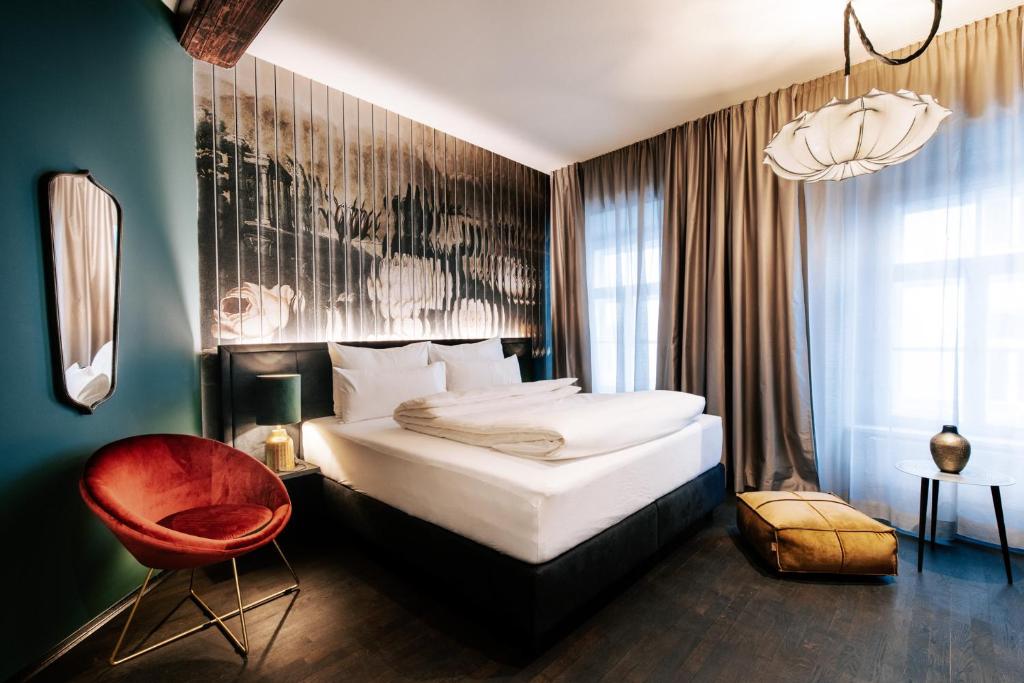 a hotel room with a bed, chair and a lamp at Aiola Living Graz in Graz