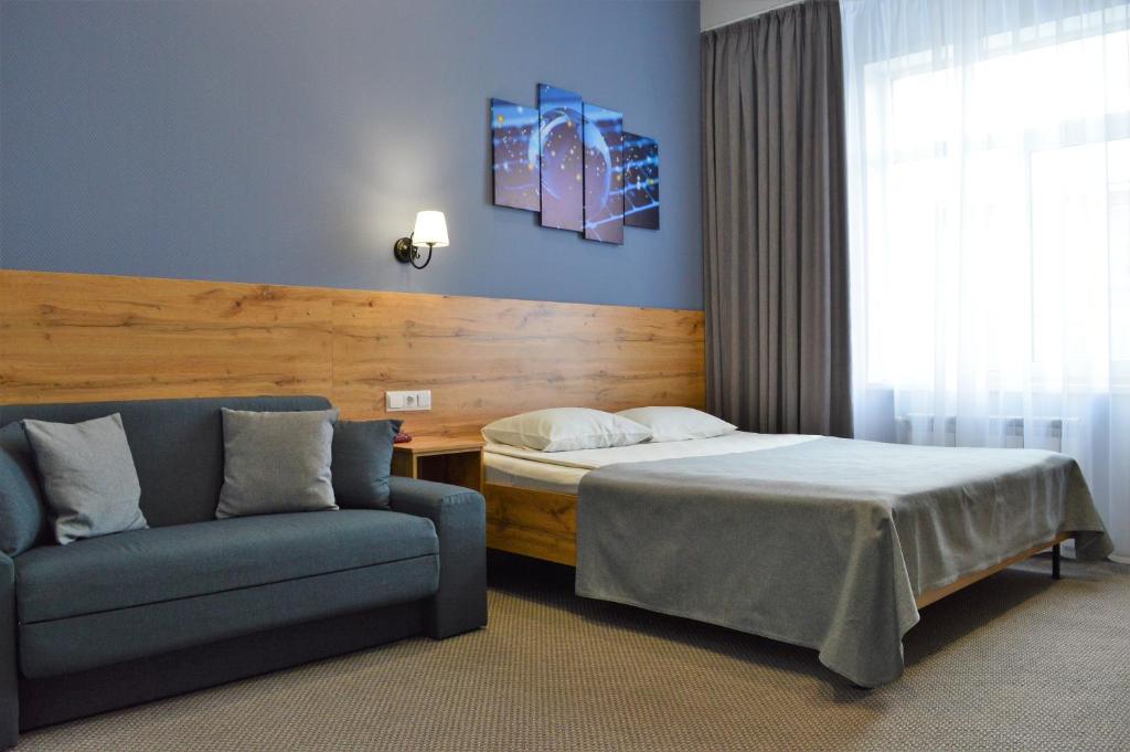 ein Schlafzimmer mit einem Bett und einem Sofa neben einem Fenster in der Unterkunft Virginia Hotel in Joschkar-Ola