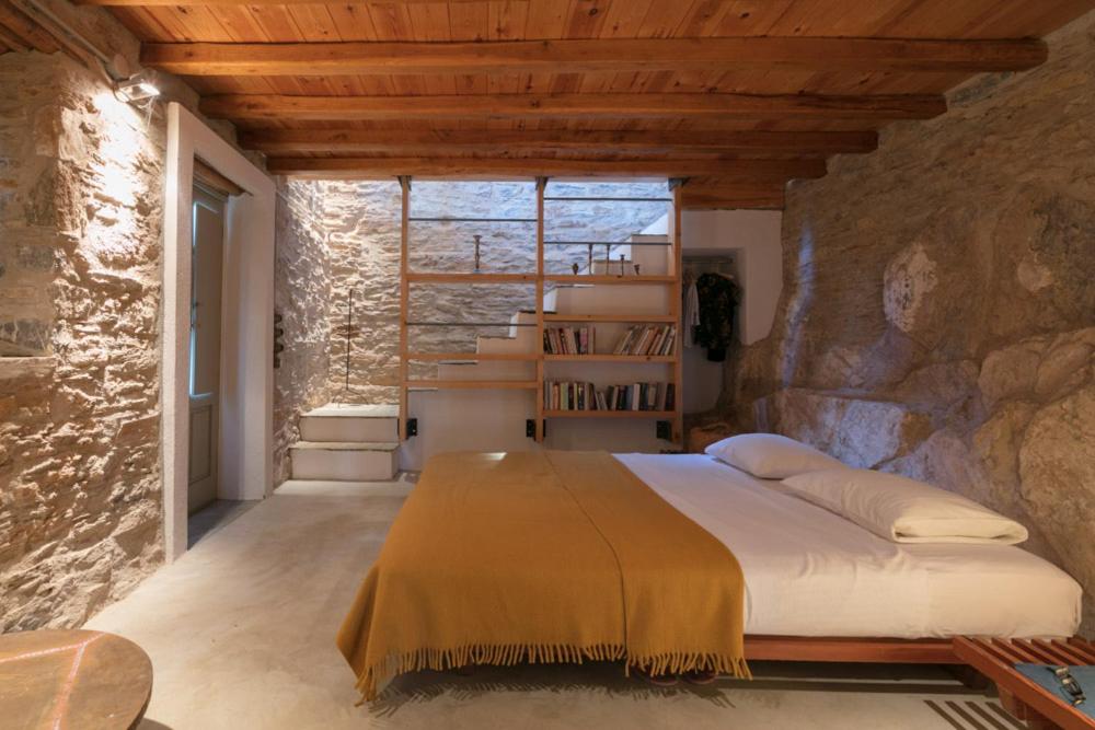 a bedroom with a large bed in a stone wall at house λ in Skiathos