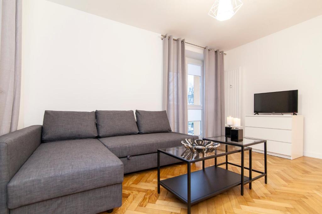 a living room with a gray couch and a table at Apartment Platinium I in Białystok