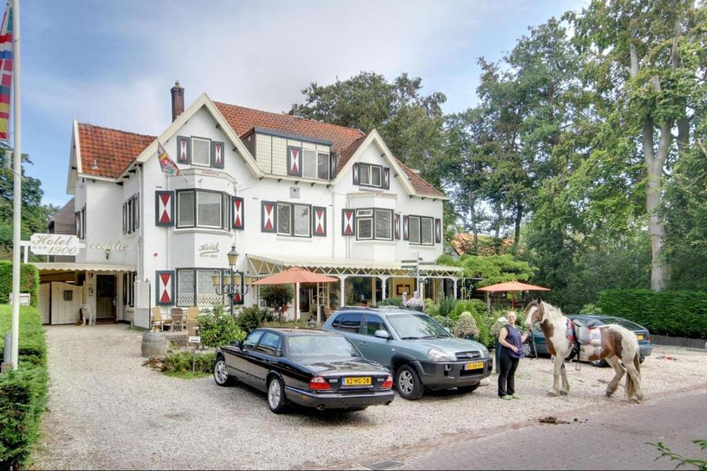 ein Pferd steht vor einem Haus mit zwei Autos in der Unterkunft Hotel 1900 in Bergen