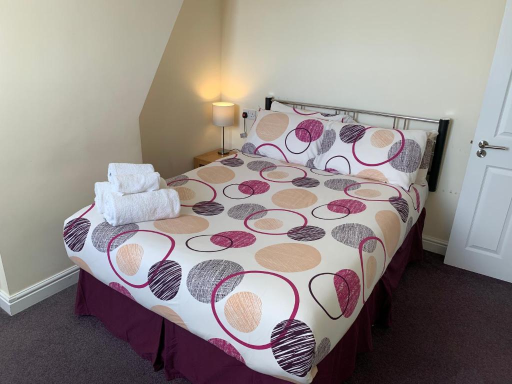 a bedroom with a bed with a floral bedspread at Austins Guest House in Cardiff