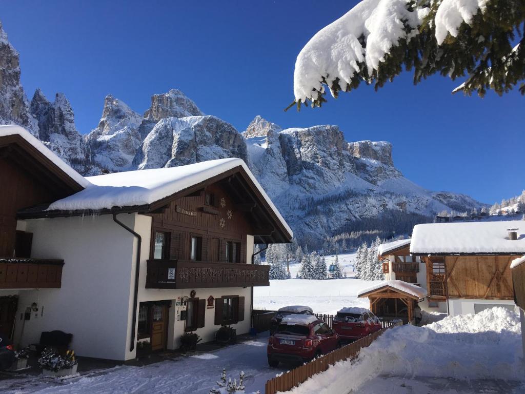 a ski lodge with snow covered mountains in the background at Apartments Fiordalisi in Colfosco