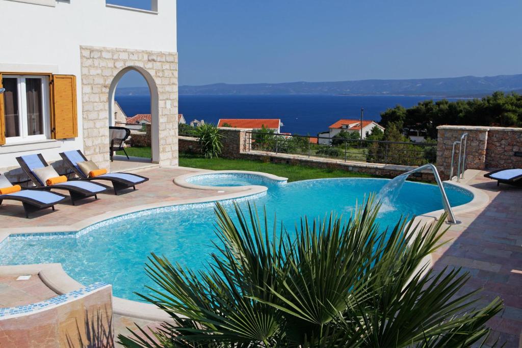 a swimming pool with lounge chairs next to a house at Villa Nera in Bol