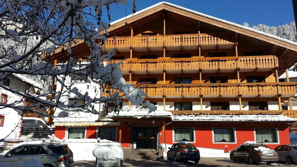 un grande edificio con un ampio balcone nella neve di Hotel Engel a Canazei