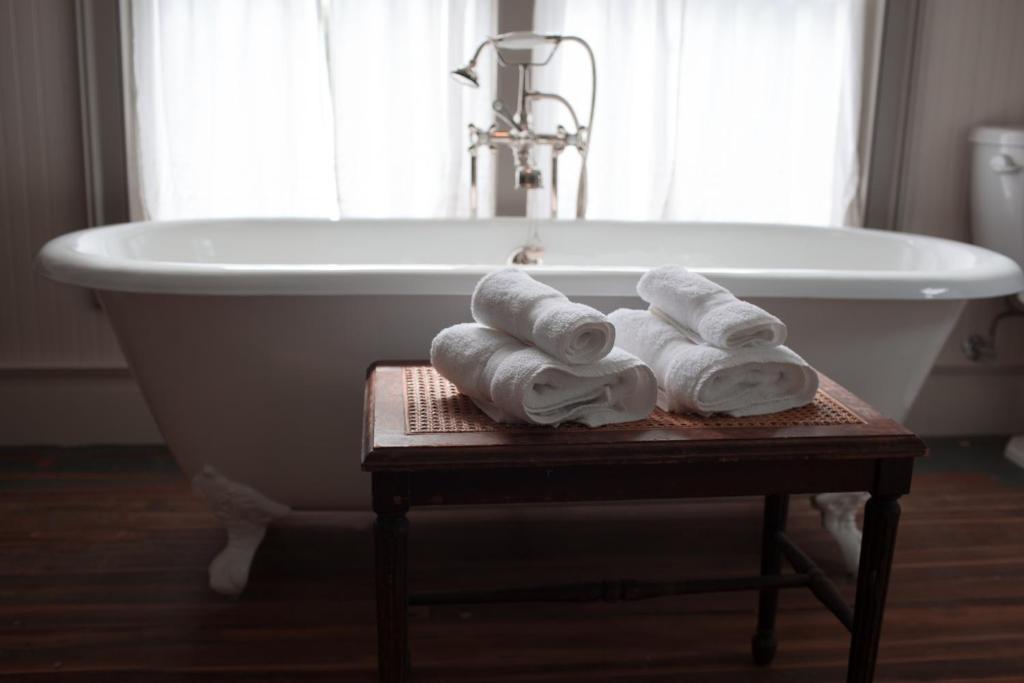 a bathroom with a bath tub with towels on a table at Stonehill's Farmhouse in Accord