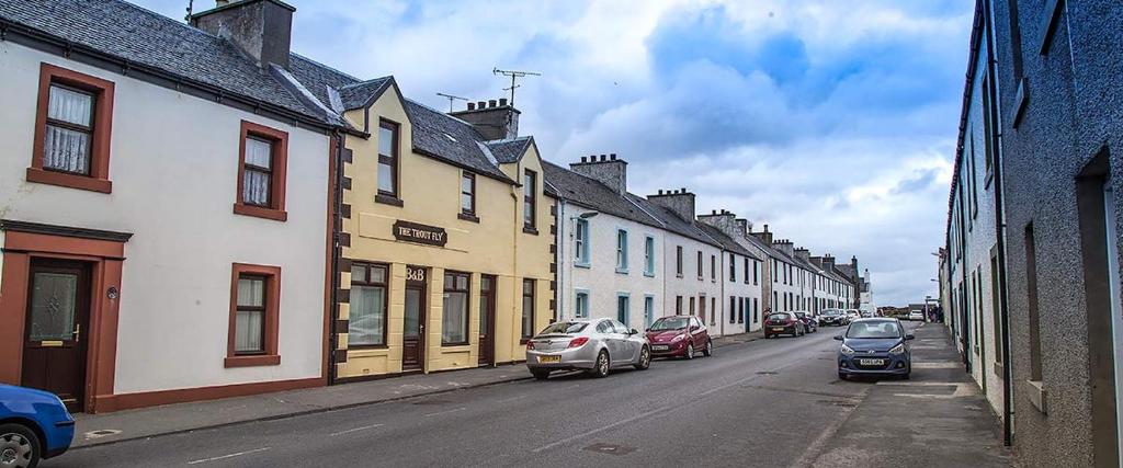 una strada cittadina con auto parcheggiate sulla strada di The Trout Fly Guest House a Port Ellen