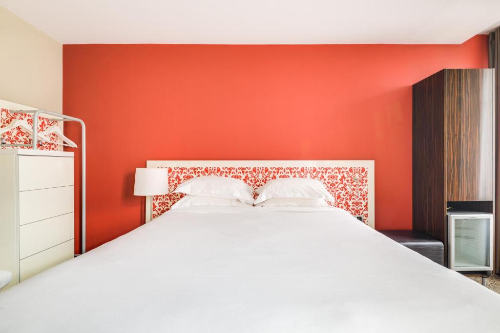 パリにあるパビリオン ナシオンの赤い壁のベッドルーム1室(白いベッド1台付)