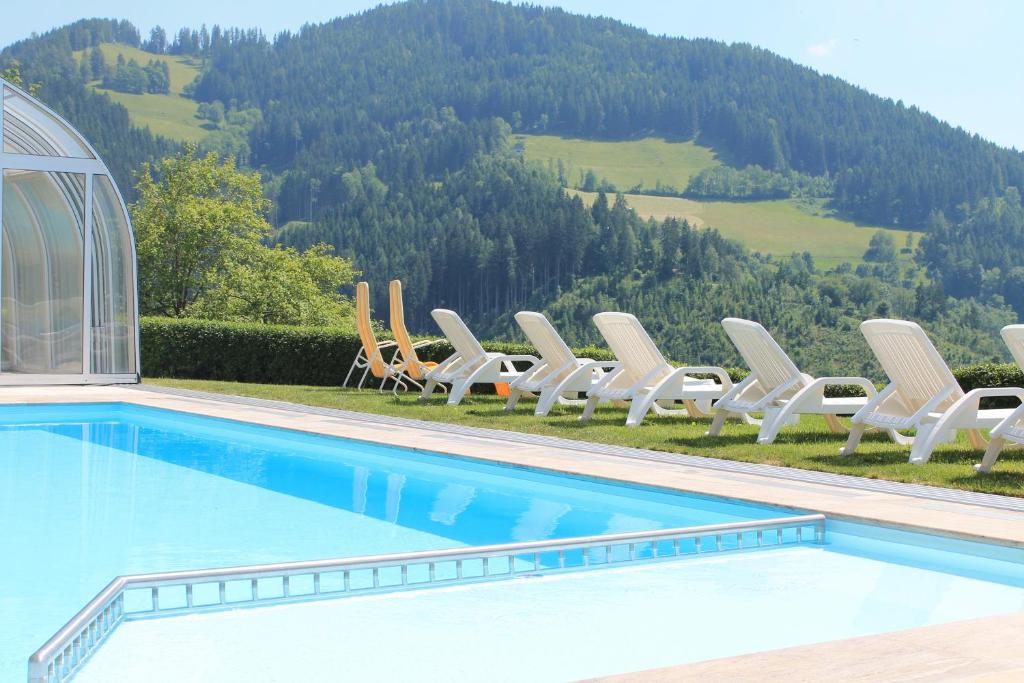 een rij stoelen en een zwembad met een berg bij Panoramadorf Saualpe in Eberstein