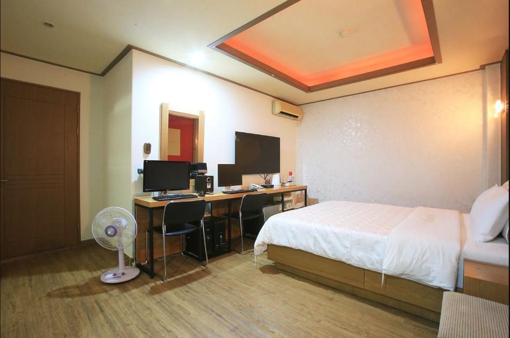 een slaapkamer met een bed en een bureau met een computer bij K2 Motel in Seoul