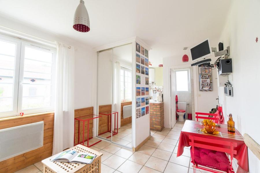 a living room with a red table and some windows at Le Studio Rouge de la Gare in Vieux-Boucau-les-Bains