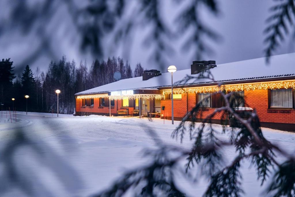 Un bâtiment dans la neige avec des lumières allumées dans l'établissement Hotelli Pielinen, à Vuonislahti