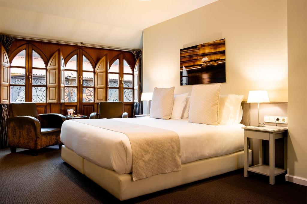 um quarto de hotel com uma cama grande e janelas em Ikonik Plaza Mercado em Salamanca