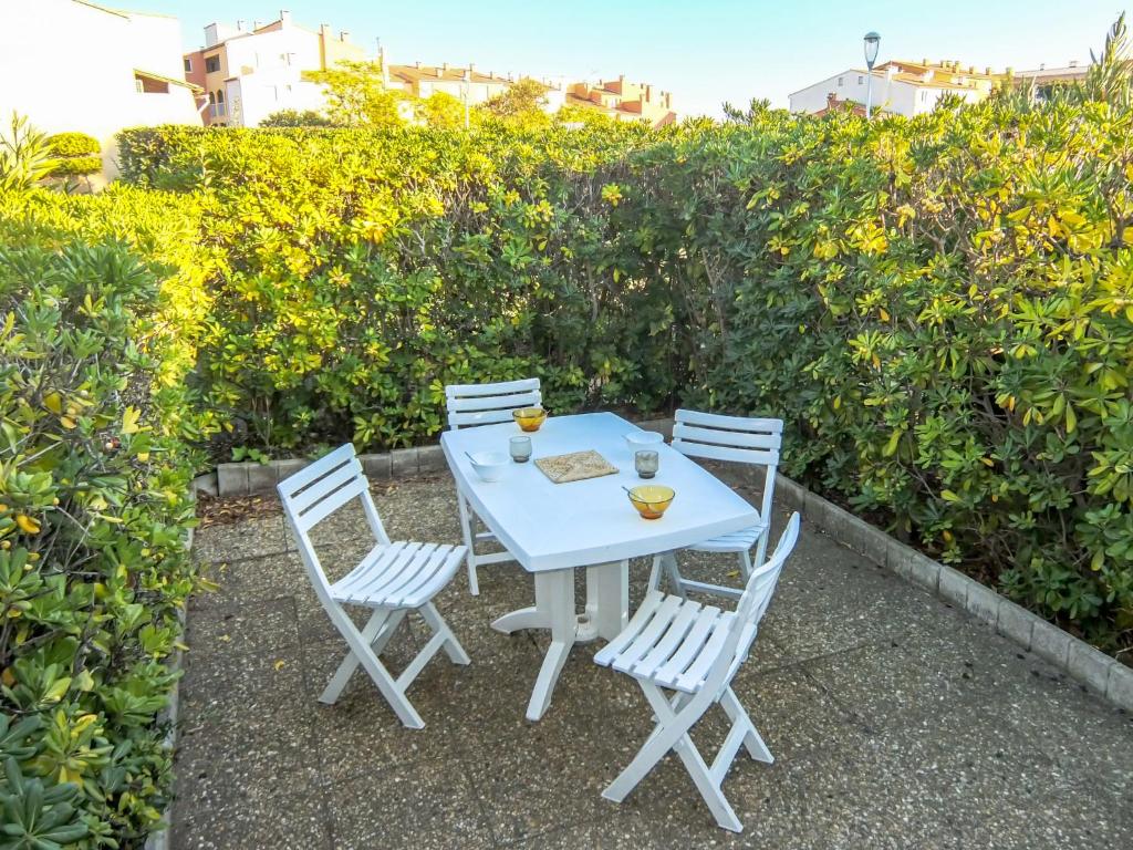 una mesa blanca y sillas con bebidas. en Apartment Les Hautes Vignes, en Cap d'Agde