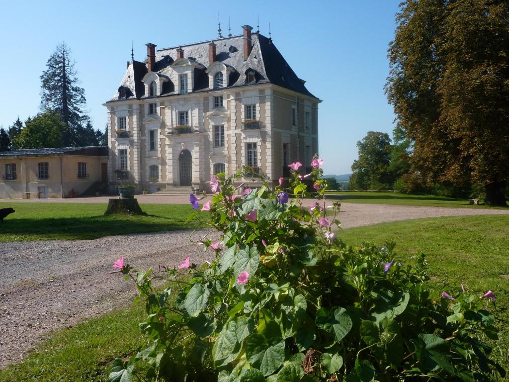 Uma casa velha com flores cor-de-rosa à frente. em Domaine de Chaligny em Saint-Hilaire-en-Morvan