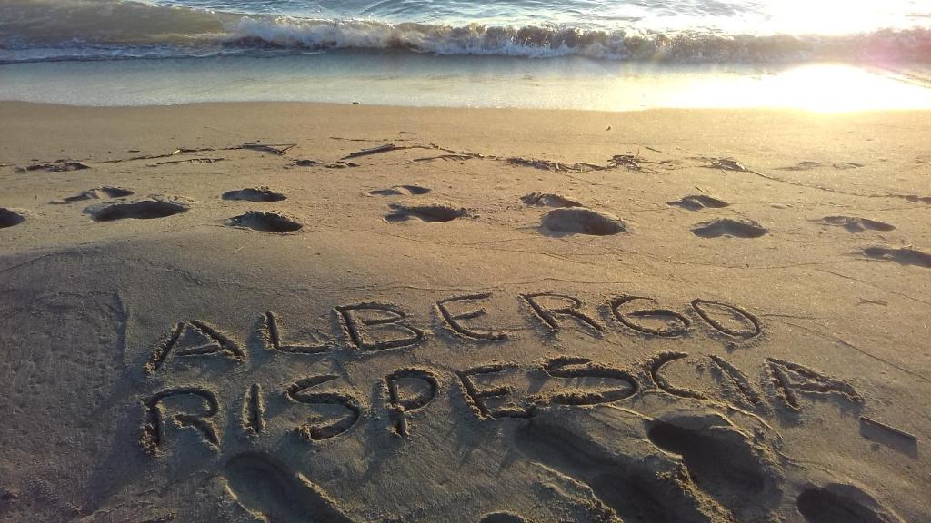 a sign written in the sand on a beach at Hotel B&B Rispescia in Rispescia