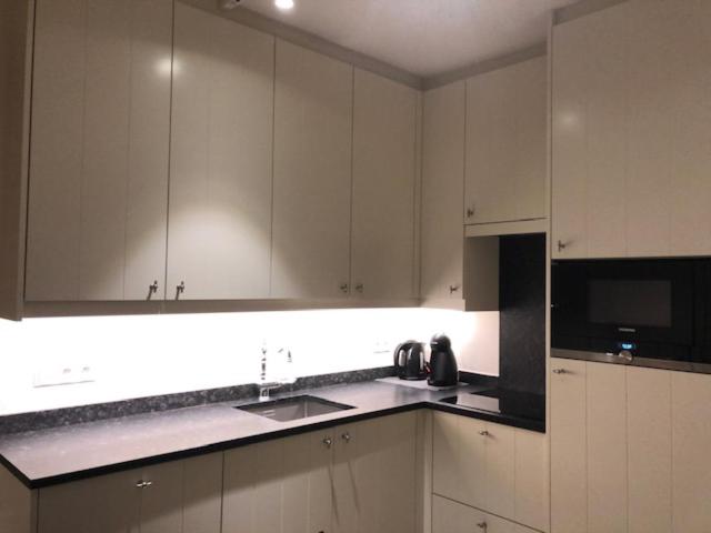 a kitchen with white cabinets and a sink and a microwave at Duinenwachter in Knokke-Heist