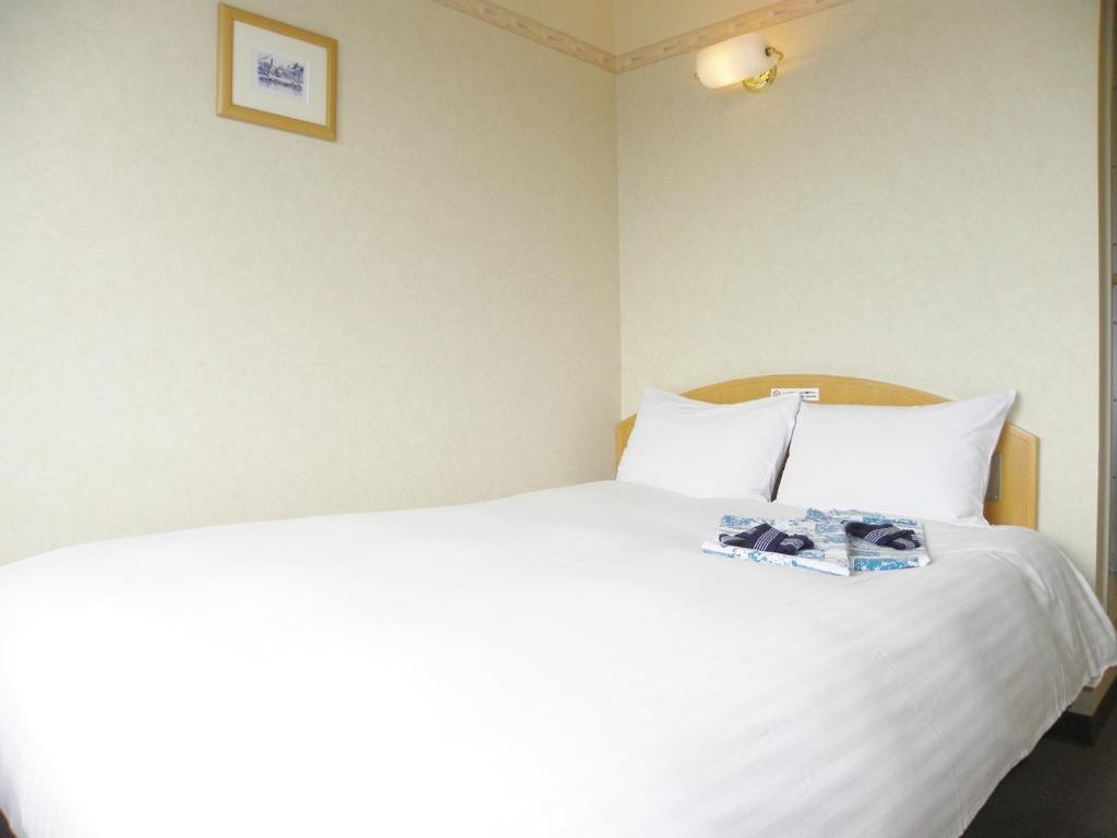 Un dormitorio con una cama blanca con un libro. en Yonezawa - Hotel / Vacation STAY 16072, en Yonezawa