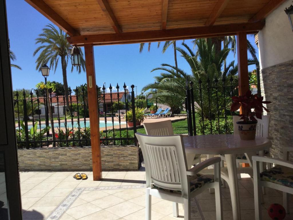 un patio con mesa, sillas y piscina en Los Porches Rosario, en Playa del Inglés