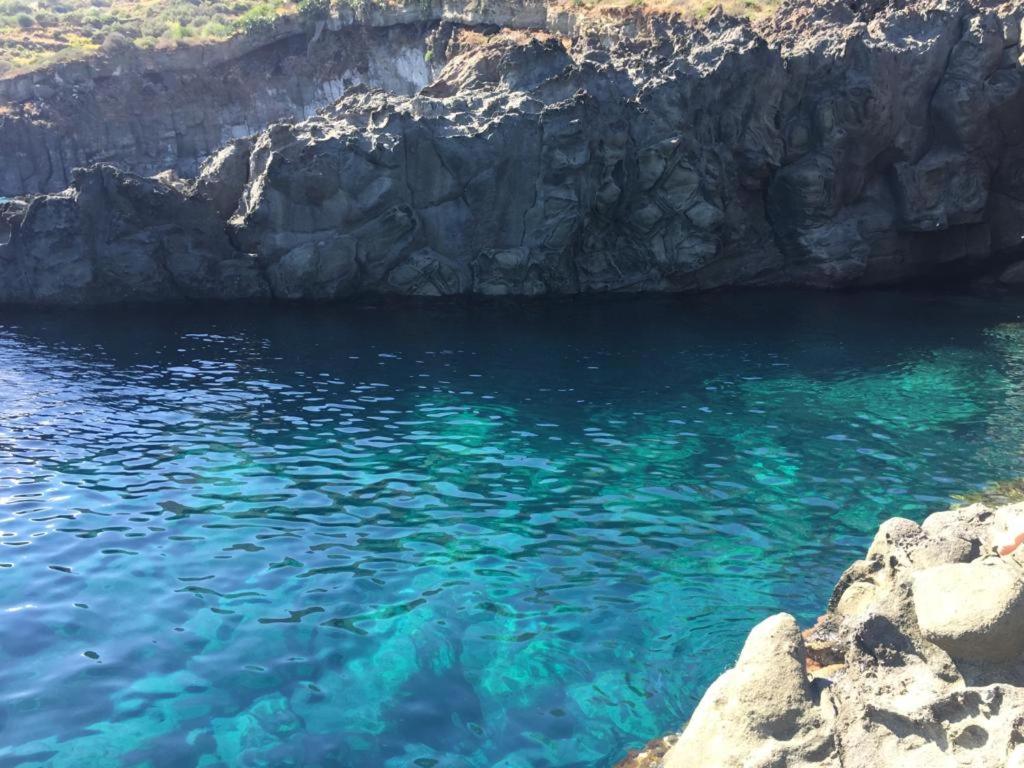 un cuerpo de agua con rocas y agua azul en I dammusi zaffiro e ambra, en Pantelleria