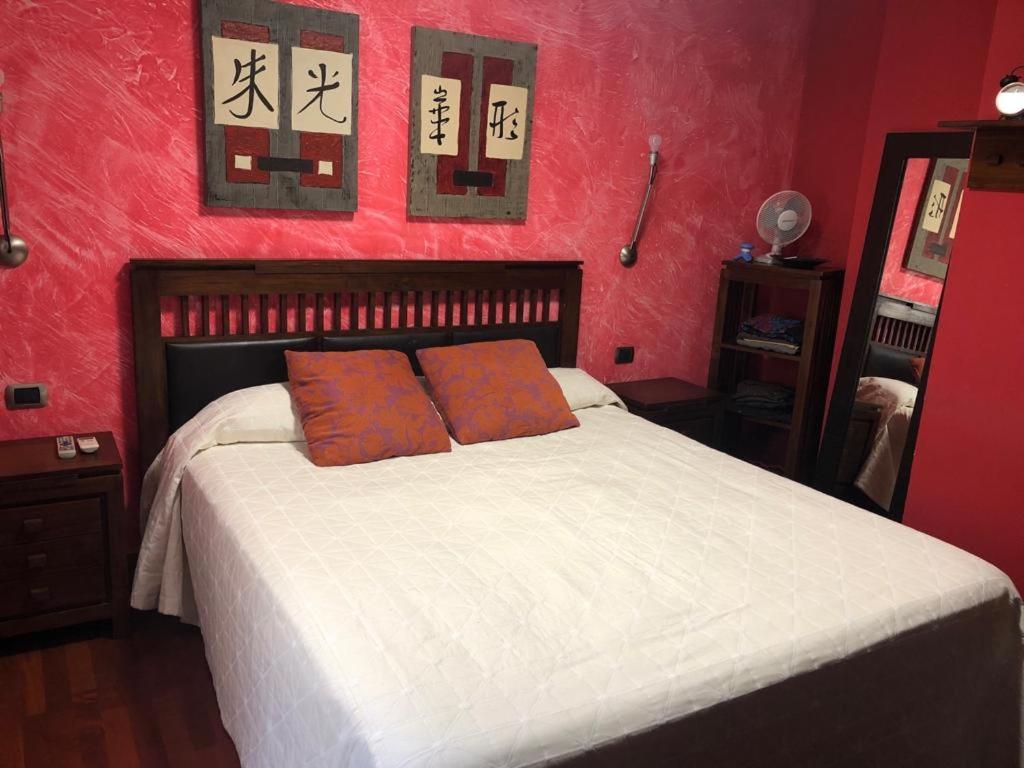 a red bedroom with a bed with two orange pillows at Casa M. in Candelaria
