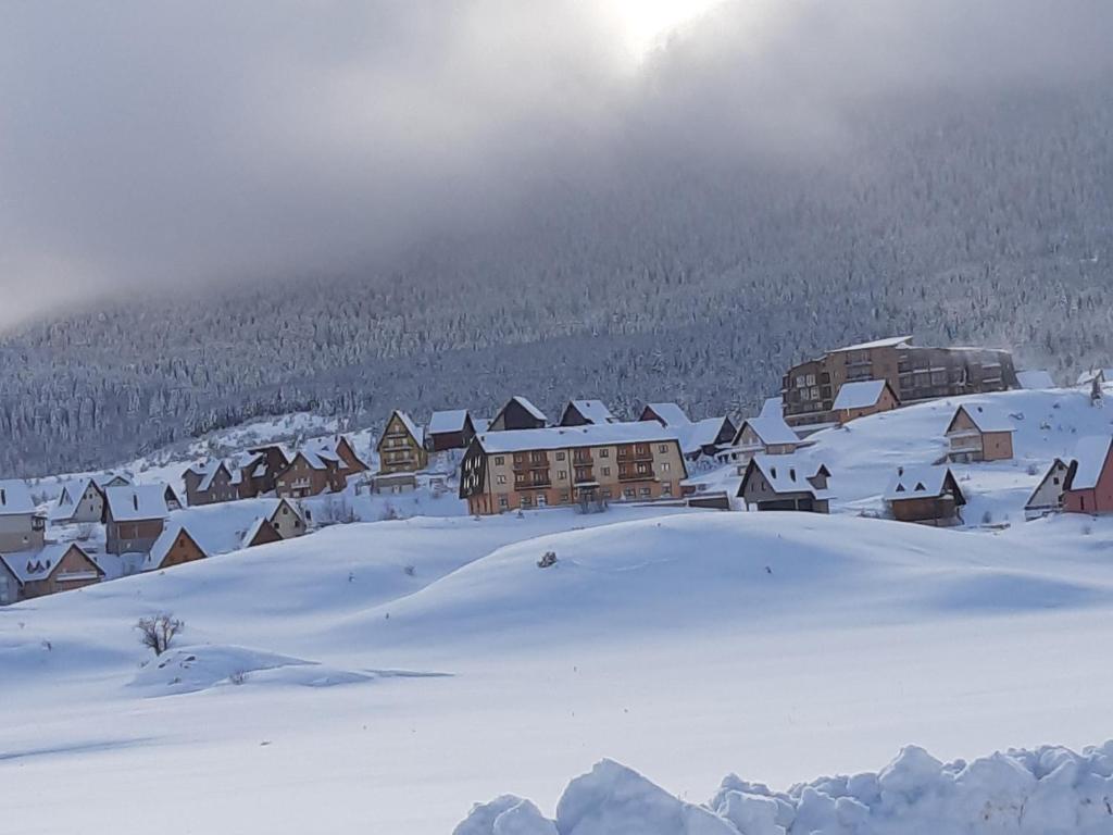 a village covered in snow with the sun in the background at Apartman Kupres Holiday in Kupres