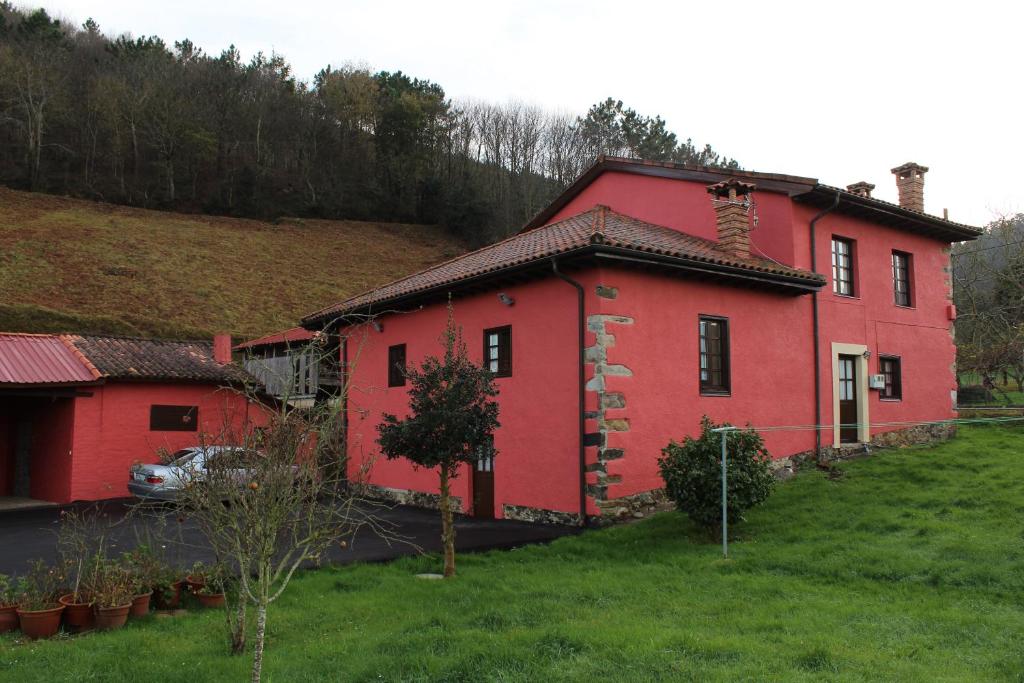 a red house sitting on top of a green field at Casa Rural Ofelia in Cudillero