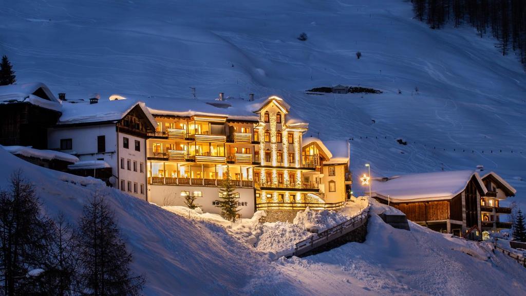 ein großes Gebäude im Schnee in der Nacht in der Unterkunft LARET private Boutique Hotel - Adults only in Samnaun