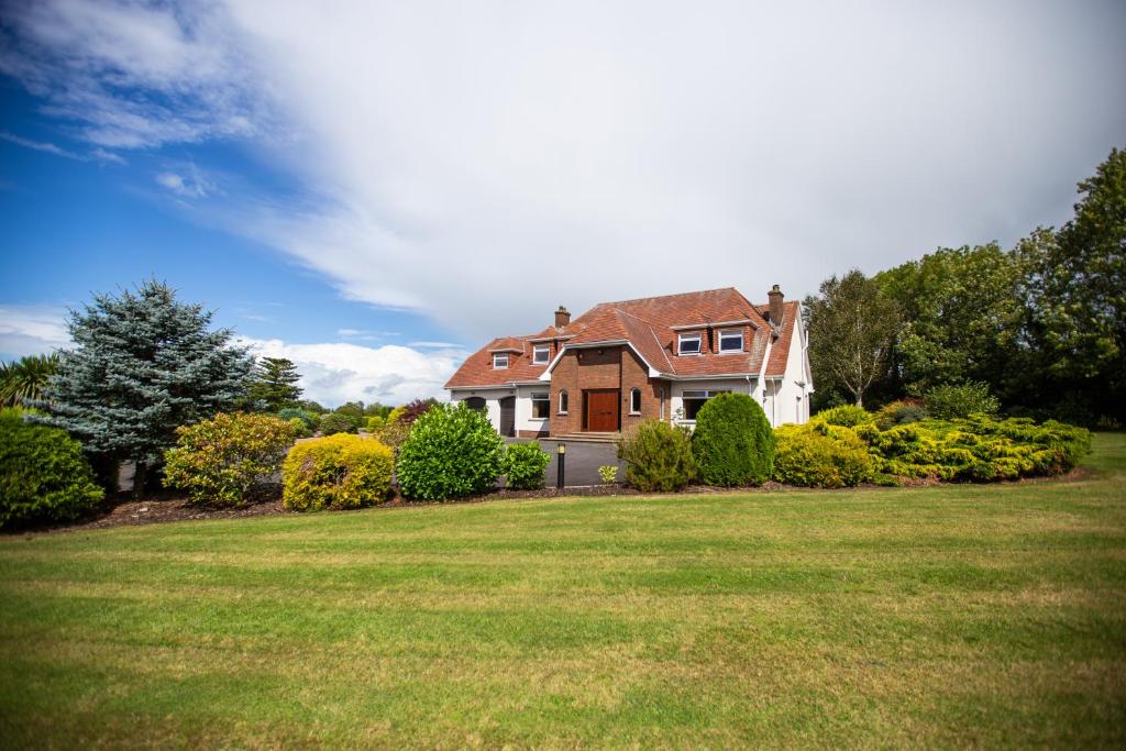 ein großes Haus mit einem großen Hof mit einem Grasfeld in der Unterkunft Luxury Manor, Private, Double Garage, Hot tub, Wifi in Ballinderry Upper