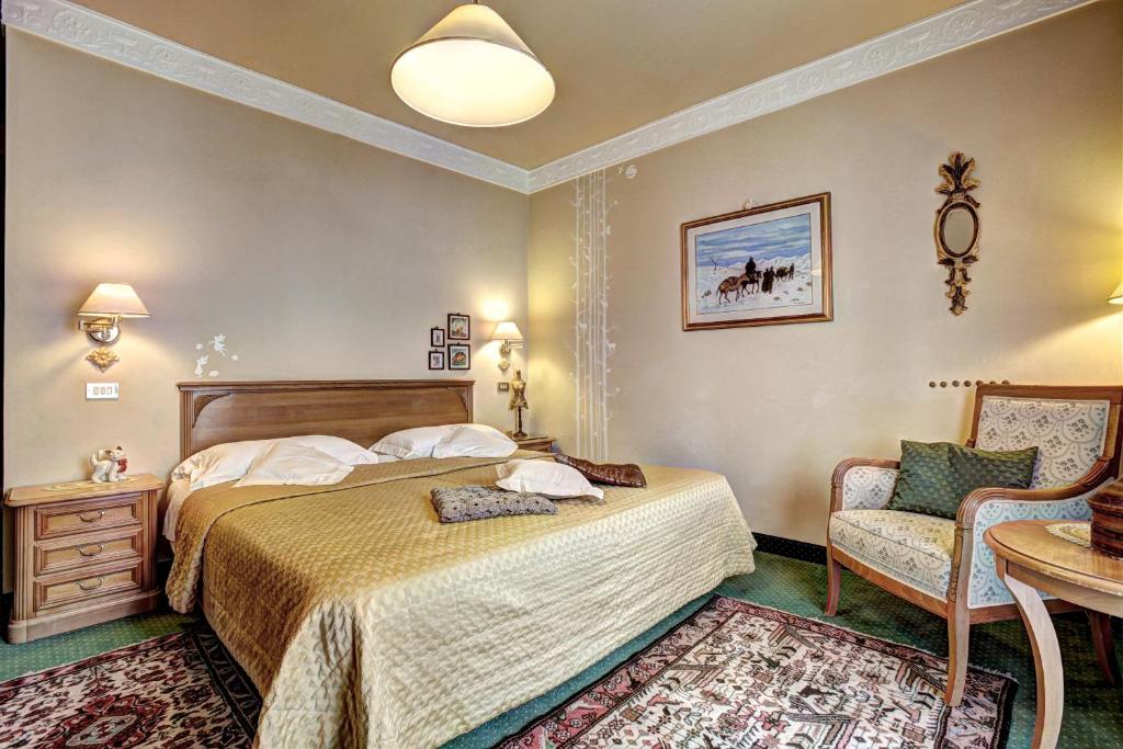 a bedroom with a bed and a chair and a table at Hotel Regina in San Martino di Castrozza