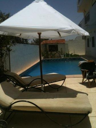 a chair and an umbrella next to a swimming pool at EDEN BEACH SAINT-LOUIS in Saint-Louis