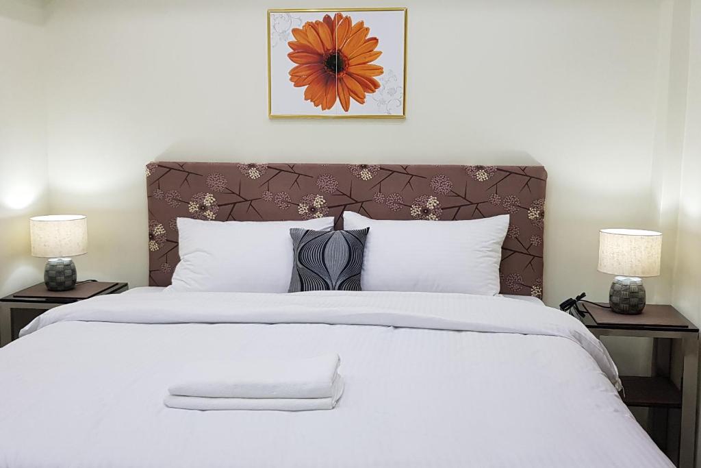 1 dormitorio con 1 cama blanca grande y 2 lámparas en Cess Summer Boutique Hotel, en Kalibo