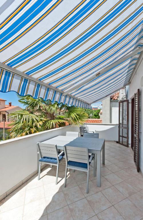 eine Terrasse mit einem Tisch und Stühlen unter einem Baldachin in der Unterkunft Apartments Alluro in Rovinj