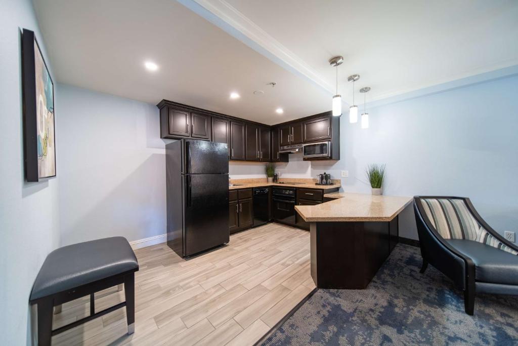 a kitchen with a black refrigerator and a table at Best Western Plus Manhattan Beach Hotel in Manhattan Beach
